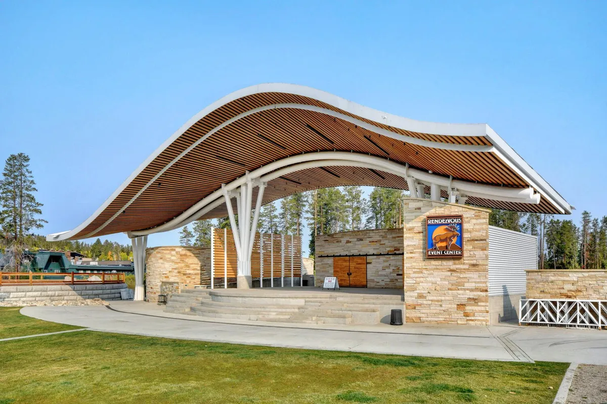 This image features the open-air amphitheater at Hideaway Park, showcasing its unique curved roof structure and stone facade. The stage area is visible and set for community events, with plenty of space for gatherings and concerts. The setting is welcoming and highlights the park as a vibrant local hub for family-friendly activities and performances.