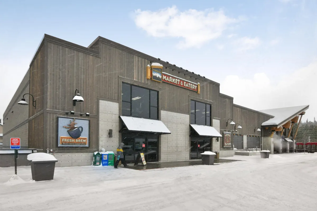 This exterior image captures the welcoming entrance and signage of the Fireside Market, with comfortable outdoor seating nearby. The market’s inviting atmosphere is evident, showing a convenient spot for guests to grab snacks, groceries, or enjoy a casual meal while mingling with the community.