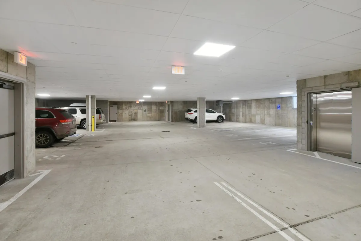 A well-lit, secure underground parking garage with parked vehicles and prominent lighting fixtures. The space is clean and organized, making it easy for residents and guests to access their vehicles comfortably in all seasons.